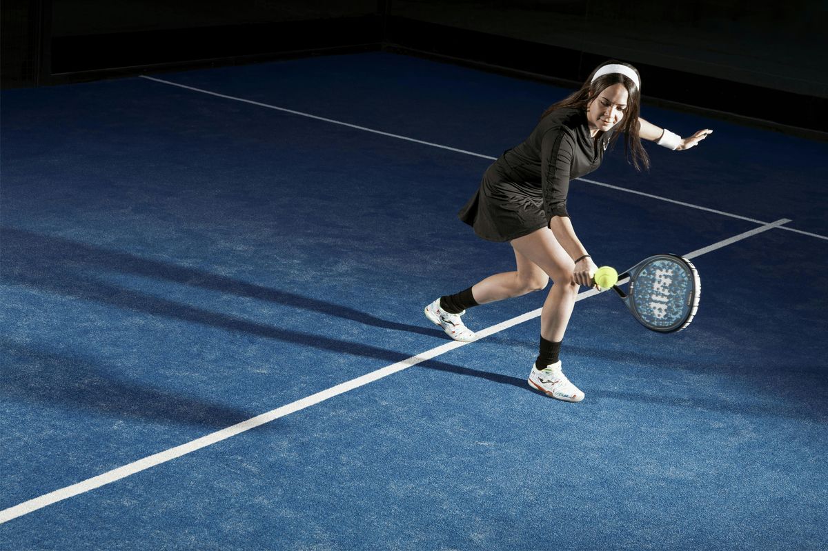 Padelspeelster strekt zich uit voor een bal tijdens een rally